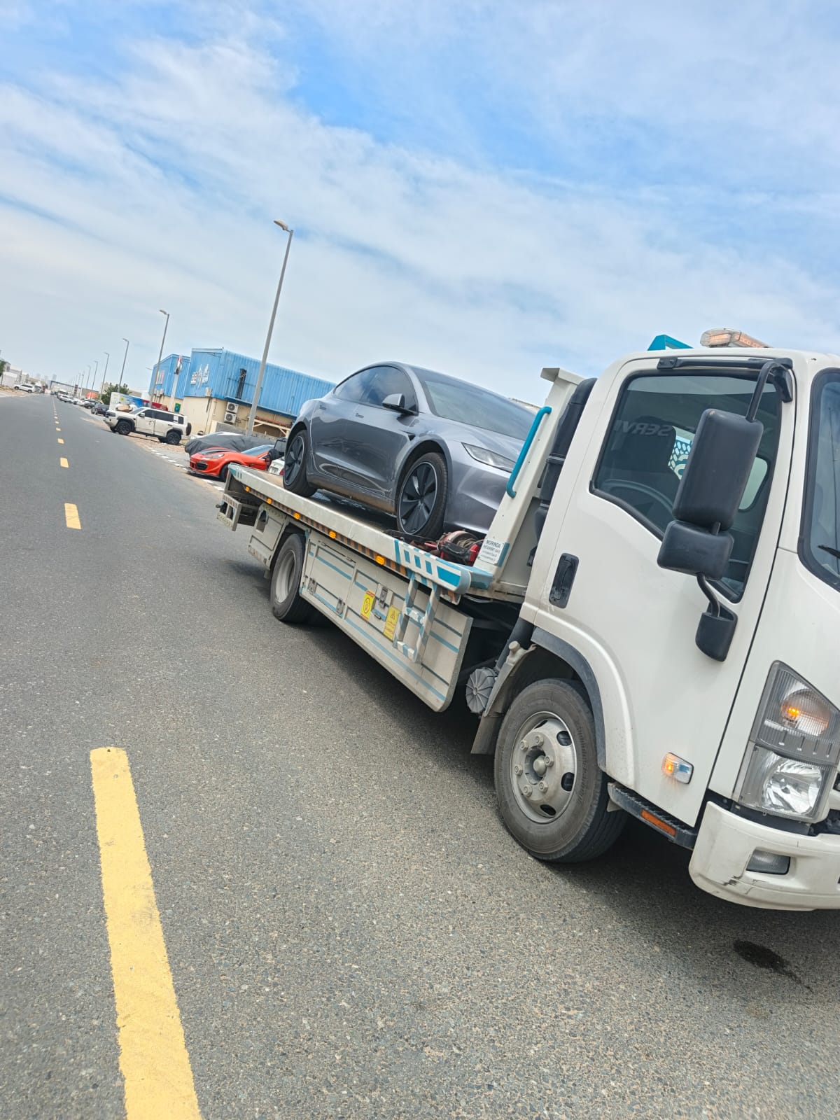Flatbed tow truck carrying a car in Sharjah